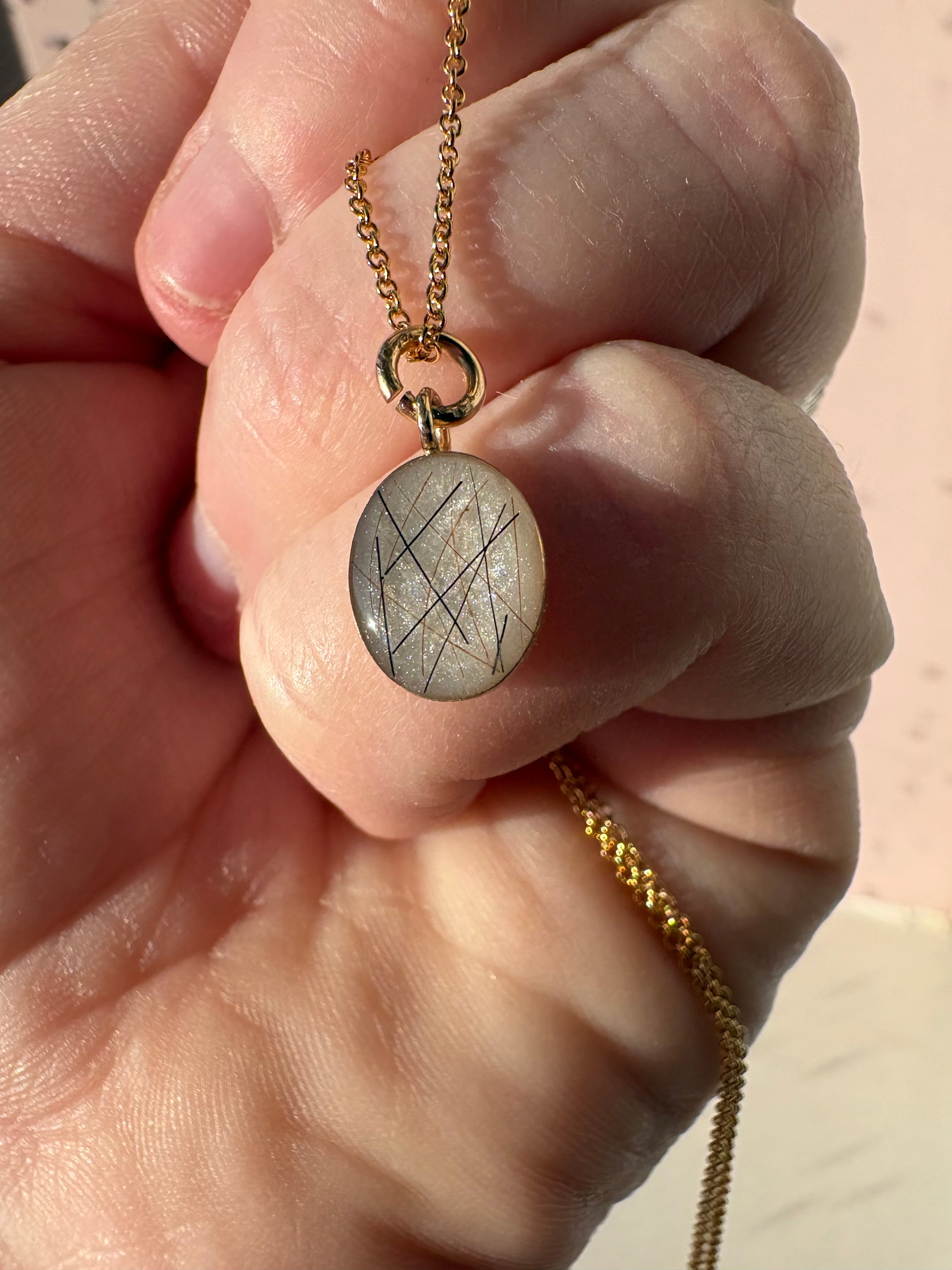 Gold filled oval pendant, with horse hair set on a white stone.