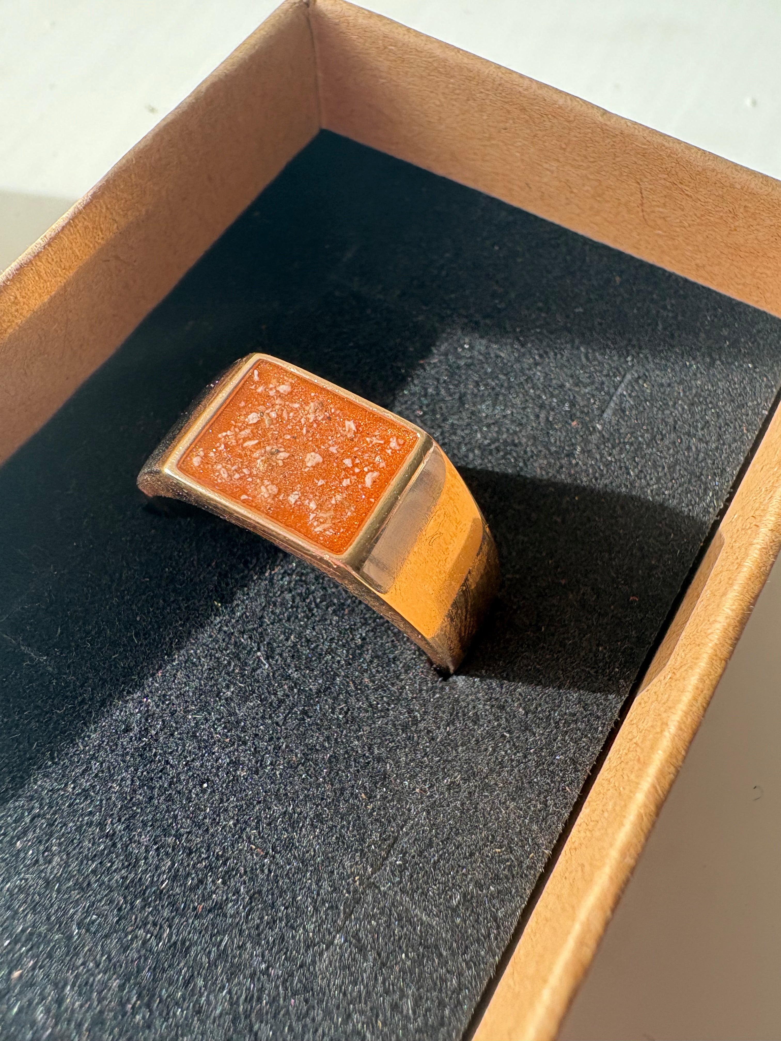 Solid gold signet ring, with ashes set in an orange stone.